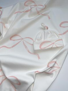 a white blanket with pink bows on it and a hat sitting on top of it