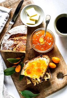 bread, jam and butter are on a cutting board with oranges next to it