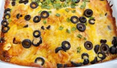 an enchilada casserole with black olives and green onions in a white dish