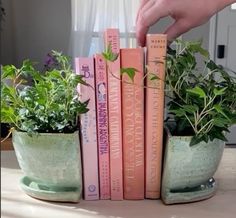 a hand is picking up some books from a planter