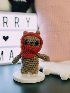 a small crocheted teddy bear wearing a red scarf