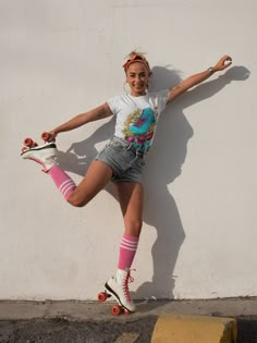 a young woman riding a skateboard next to a white wall with roller blades on it