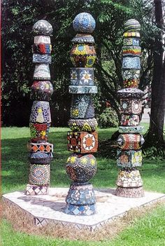 a group of colorful vases sitting on top of a cement slab in the grass