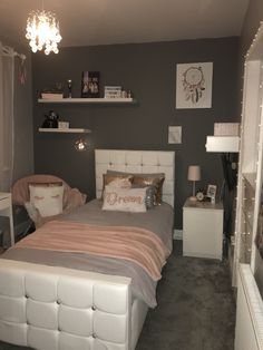 a bed room with a neatly made bed and a chandelier hanging from the ceiling