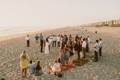 a large group of people standing on top of a sandy beach next to the ocean