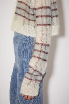 a woman is wearing a sweater and jeans