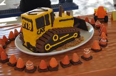 there is a cake made to look like a bulldozer on the table with construction cones around it