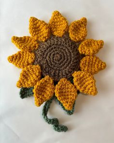 a crocheted sunflower is shown on a white surface