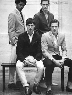 black and white photograph of four men sitting on a bench