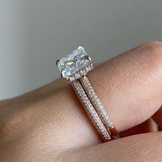 a woman's hand holding a diamond ring with two bands on it and an engagement band