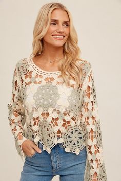 a woman wearing a white crochet top with long sleeves and an openwork design