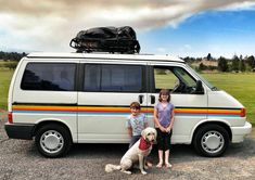 two children and a dog standing in front of a van