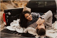 a man and woman laying in the back of a pick up truck