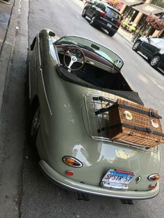 an old car is parked on the side of the road with its trunk in the back