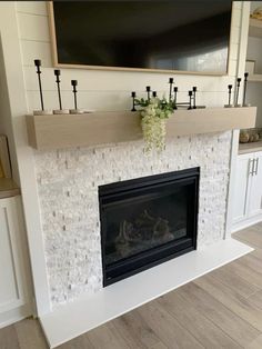 a fireplace with a tv above it and some flowers on the mantle in front of it