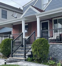 two story brick house with black iron railings and white trim on the front porch