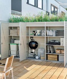 an outdoor storage unit with plants on the top and shelves below, in front of a building