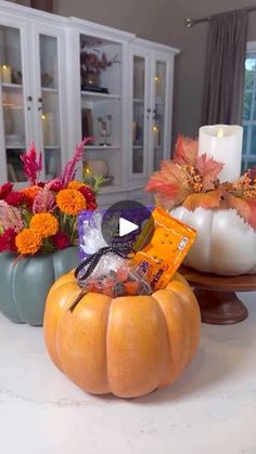 two pumpkins sitting on top of a counter next to candles and other decorative items