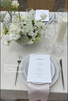 the table is set with white flowers and silverware