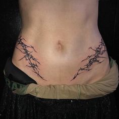 a woman's stomach with barbed wire tattoo on her side and the bottom part of her body