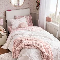 a bedroom with pink wallpaper and white bedding in the corner next to a window