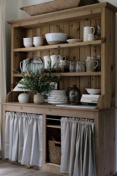 a wooden hutch filled with dishes and cups