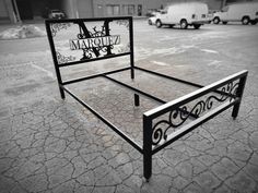 a black and white photo of a bed frame in the middle of a parking lot