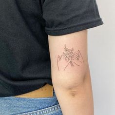 a woman's arm with a tattoo on it that has two hands holding flowers