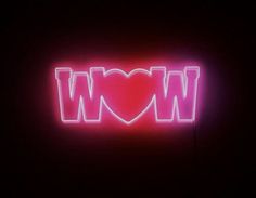 a neon sign that says wow with a heart in the middle on a dark background