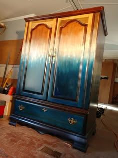 an armoire painted with blue and orange ombreaches in a room that is being worked on