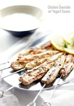 grilled chicken skewers with lemon wedges and yogurt sauce on a plate