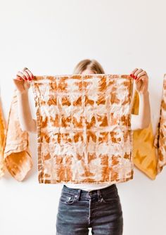 a woman holding up an orange and white piece of cloth in front of her face