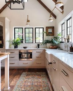 a kitchen with wooden floors and white walls, an area rug on the floor is in front of the stove