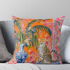 an orange pillow with leopards and flowers on the front is sitting on a couch