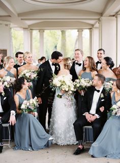 a large group of people standing around each other in formal wear and tuxedos