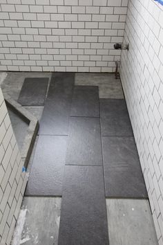 a bathroom that has some tiles on the floor and walls, with no shower curtain