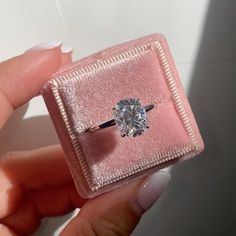 a person holding a ring with a diamond in it's box on their finger