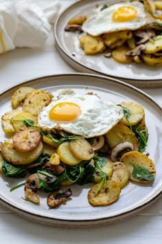 two plates filled with potatoes and an egg on top of them next to some bread