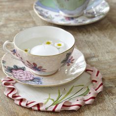 two tea cups and saucers sitting on top of a wooden table