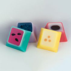 three different colored dices sitting next to each other on a white surface with black dots