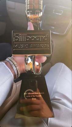 a person holding up an award in their hand while sitting in a car with the sun shining on them