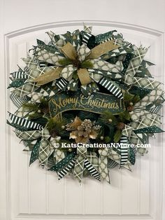 a christmas wreath on the front door with green and gold ribbons, pine cones, berries and mists