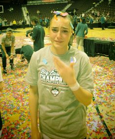 a woman standing in front of a basketball court with confetti on the floor