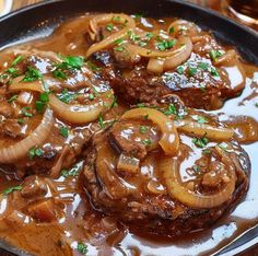 some meat with onions and gravy in a skillet on a wooden table