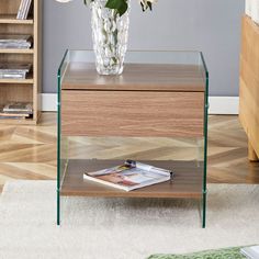 a glass table with flowers in it on the floor next to a bookshelf