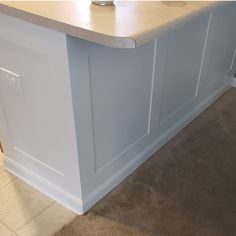 a white kitchen island sitting next to a wall with a counter top on one side and a sink on the other