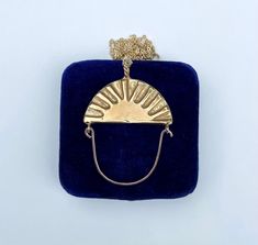 The night and day charm holder necklace is part of Serpentine's collection of original jewelry designs which were first lovingly hand carved from wax then cast locally in metal. Featuring a half-oval shaped brass reversible charm with a rope patterned bail. One side depicts a large sunburst and the other has a crescent moon and stars. It has a hand-formed hinged gold-filled wire that can be unhooked to slide your favorite charms on and off. It comes on a long gold-filled chain that is finished w Hand Cast Brass Necklace Perfect For Gifts, Hand Cast Brass Necklace For Gift, Adjustable Hand Cast Round Pendant Necklaces, Artisan Crescent Necklace For Gift, Reversible Jewelry, Charm Holder Necklace, Stars Jewelry, Original Jewelry Design, Charm Holder