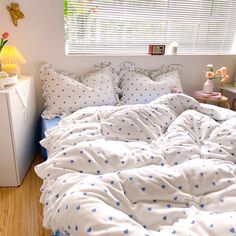 a bed with blue and white polka dots on the comforter is in front of a window