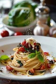 a white plate topped with pasta covered in sauce and garnished with fresh basil