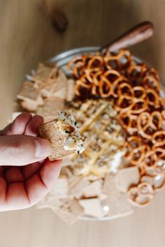 a hand holding a cracker over a bowl of food